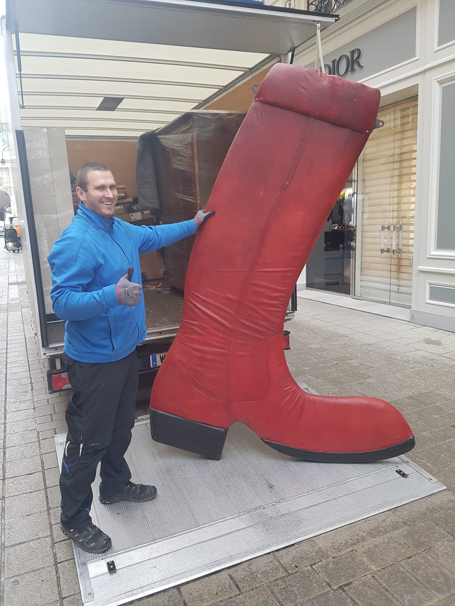 A-Team-Mitarbeiter transportiert eine übergroße rote Stiefel-Skulptur