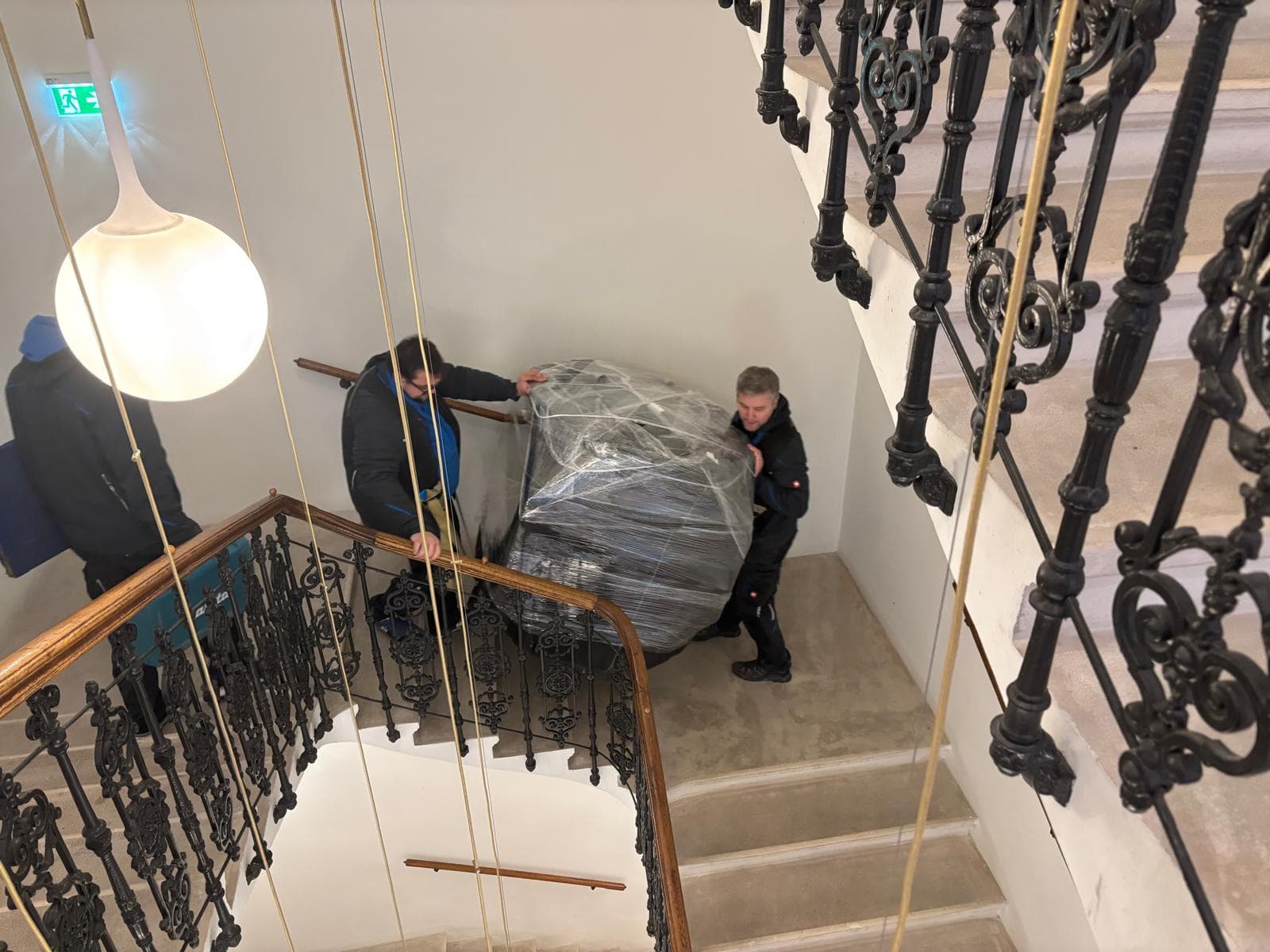 Das A-Team transportiert eine sorgfältig verpackte Wiener Würfeluhr durch ein Stiegenhaus