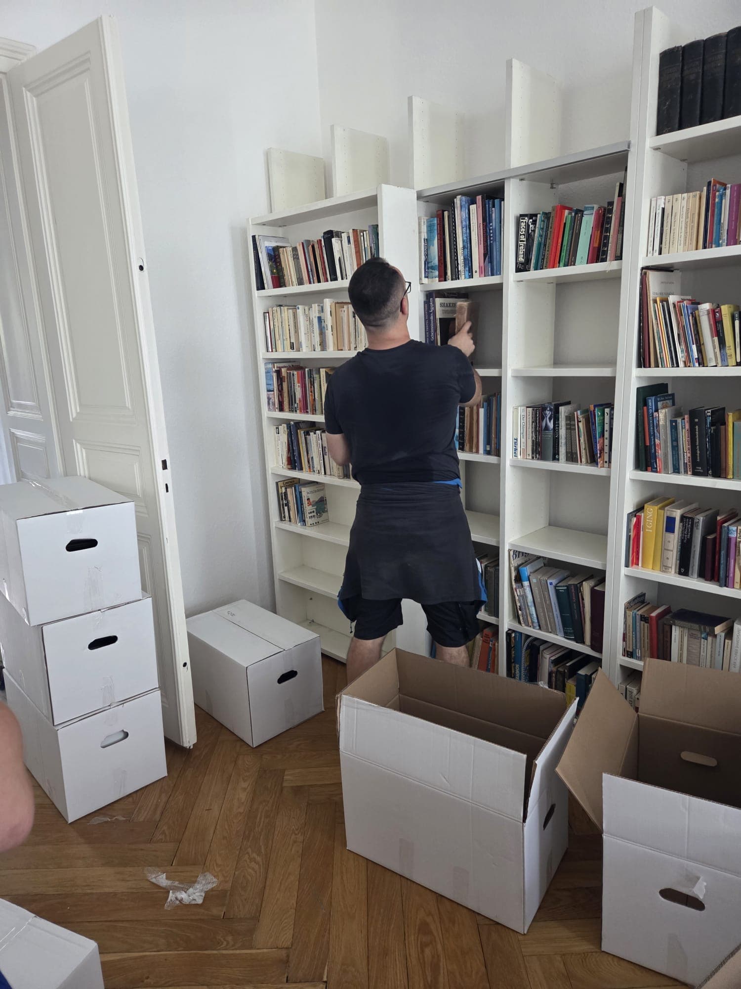 A-Team-Mitarbeiter räumt Bücher aus Umzugskartons in ein Regal ein