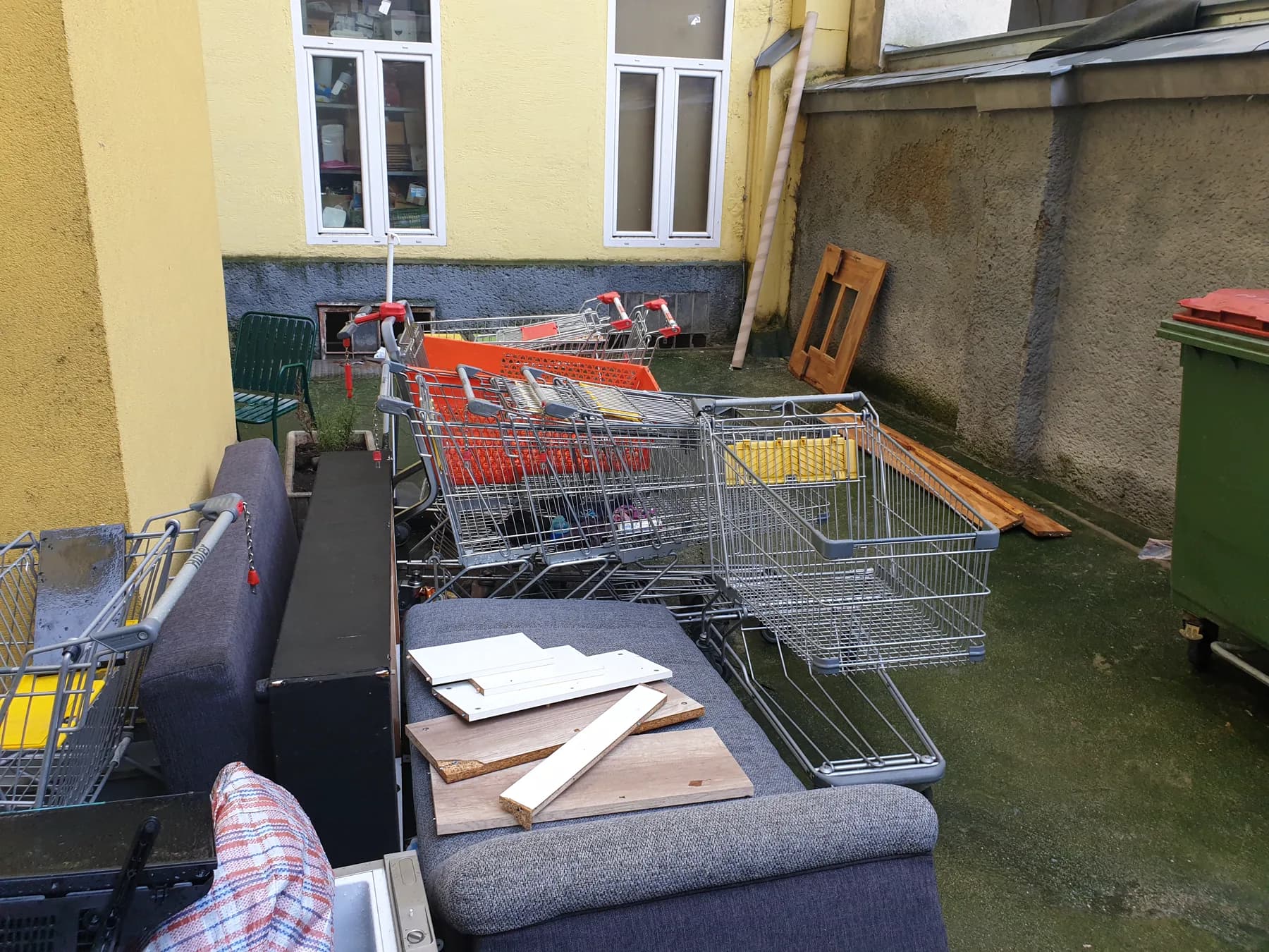 Vollgestellter Innenhof mit Möbeln, Einkaufswagen und Haushaltsgegenständen